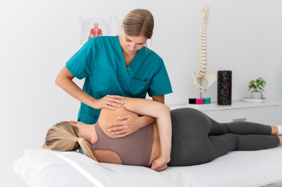 Physiotherapist providing manual therapy to a woman during a post-pregnancy physiotherapy session in a modern rehabilitation clinic.