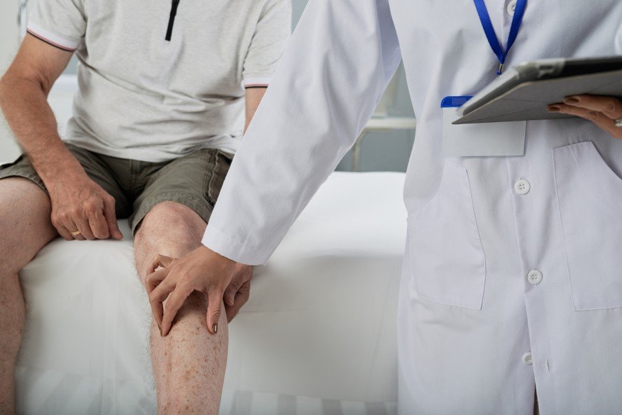 Doctor examining a patient’s knee during a medical consultation.