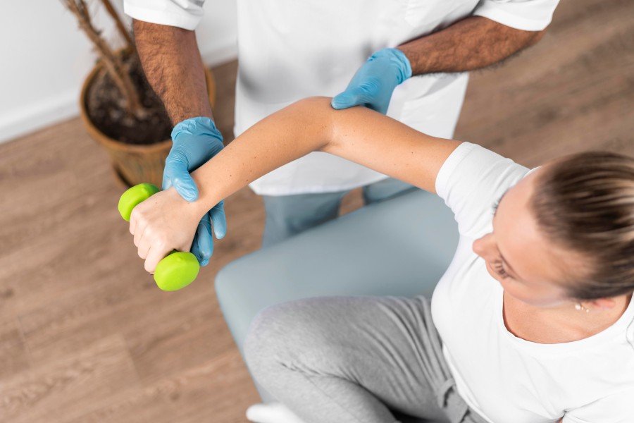 Physiotherapist guiding a woman through a shoulder mobility exercise at home