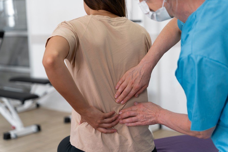 Healthcare professional examining a woman with lower back pain.