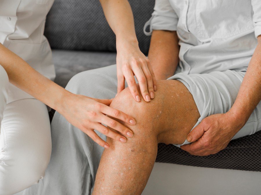 Elderly knee pain physio session with a physiotherapist examining an older patient's knee to assess joint pain and mobility