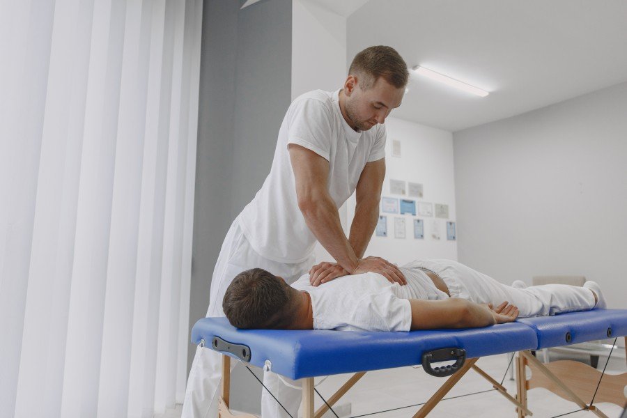 Chiropractor performing a back treatment on a patient lying on a therapy table
