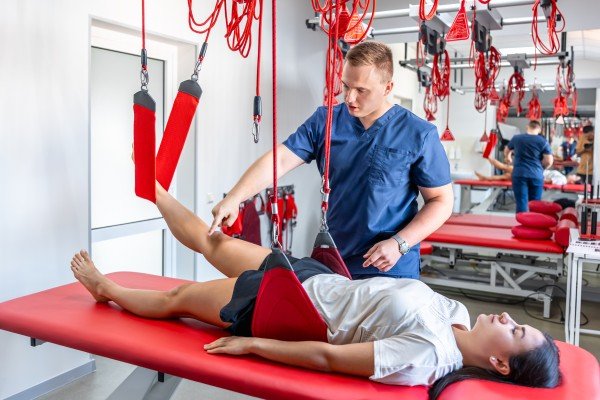 Physiotherapist assisting a patient with suspension strap exercises at a Physiotherapist center